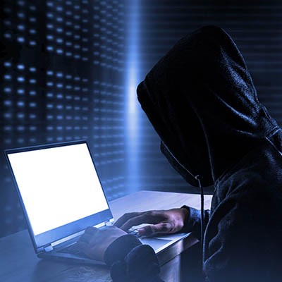 hooded hacker hacking on a laptop
